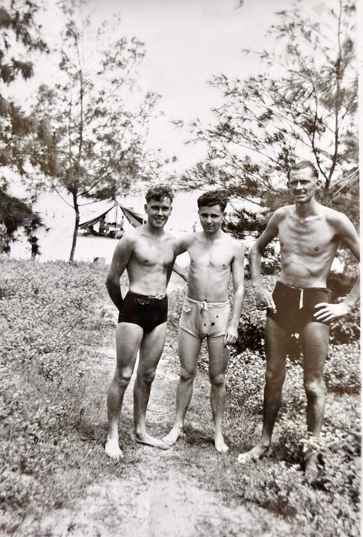 Black and white photograph of Allan O'Neill's father Frank with two friends, posing in swimming turnks at an Army camp in Hong Kong, 1955.