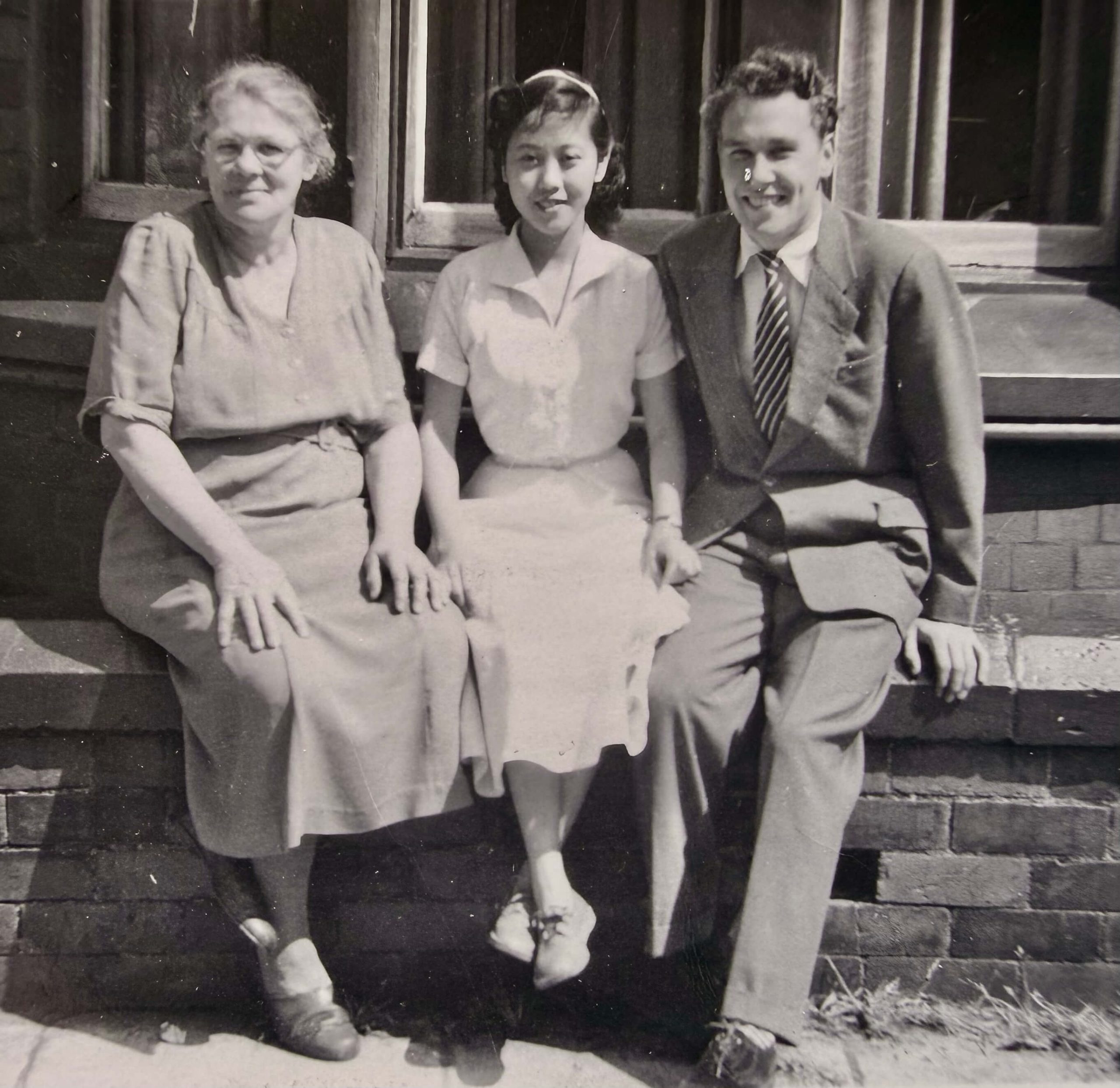 Black and white photograph of Allan O'Neill's mother Yuet Wah and father Frank sitting on a wall with his grandmother Nellie in Padiham Lancashire in the mid-1950s.