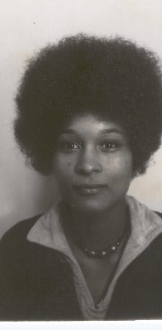Black-and-white portrait of Sylvia Erike at Lancaster University, facing the camera with a large Afro hairstyle and beaded necklace.