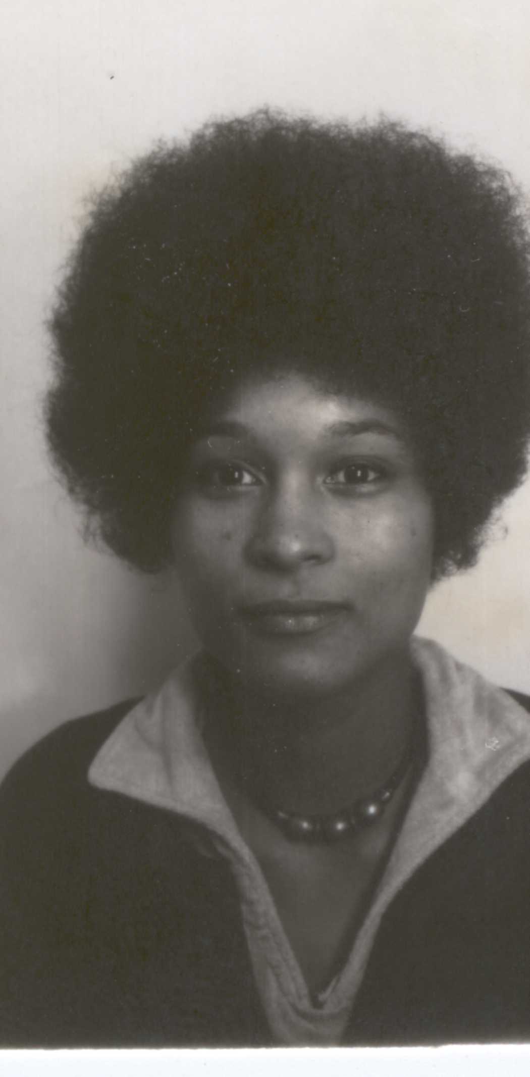 Black-and-white portrait of Sylvia Erike at Lancaster University, facing the camera with a large Afro hairstyle and beaded necklace.