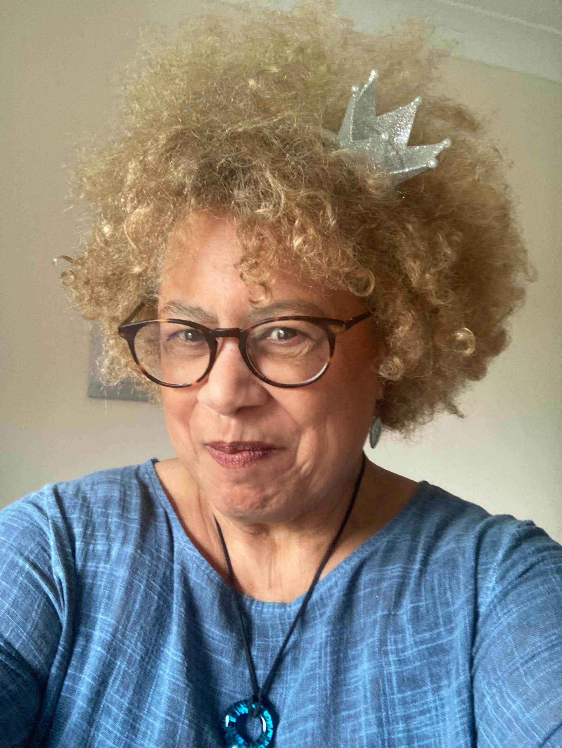 Portrait of Tina Shingler smiling at the camera, wearing glasses and a blue top.