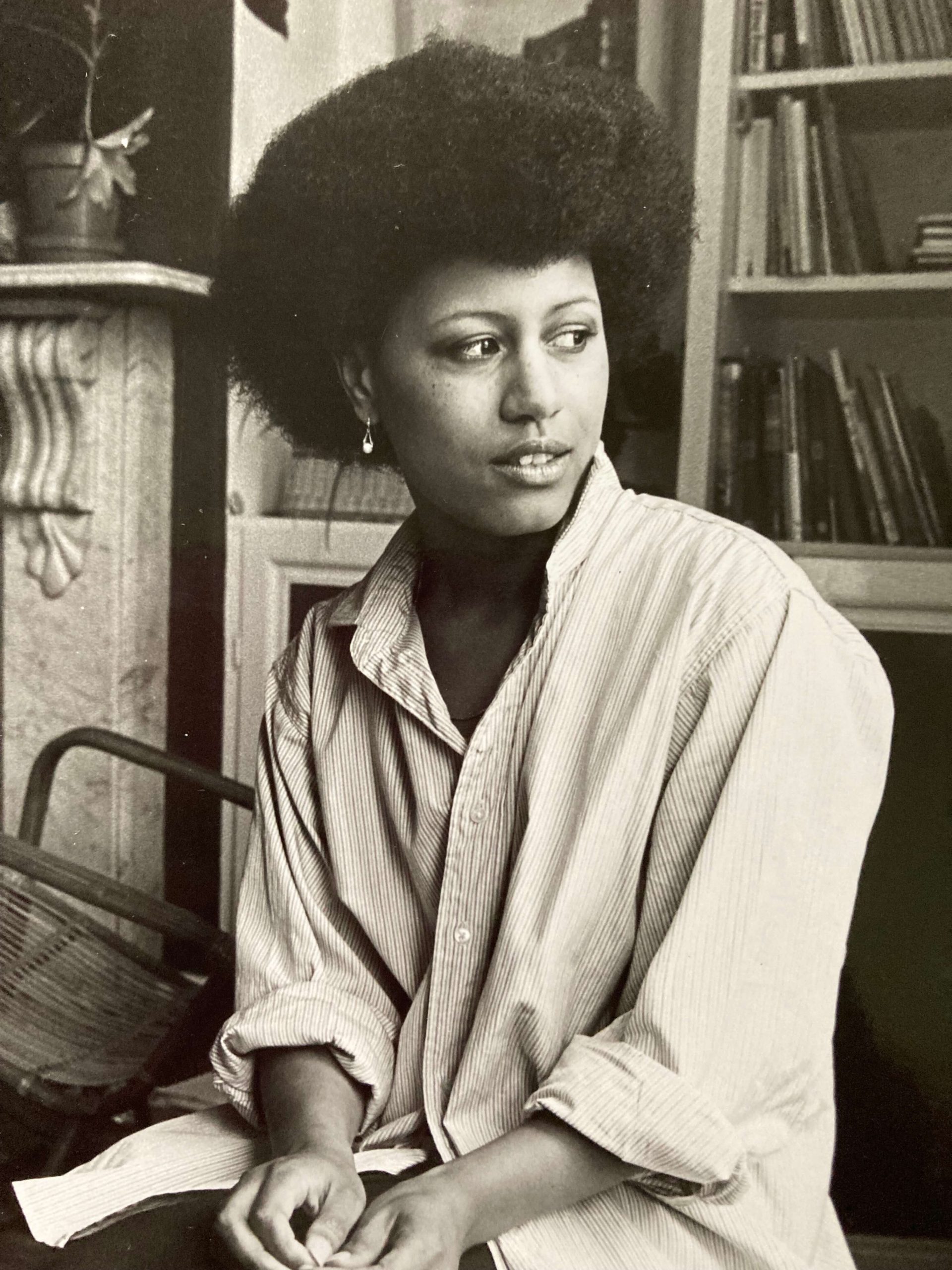 Black-and-white portrait of Tina Shingler as a young woman, seated indoors with an Afro hairstyle and looking to one side.