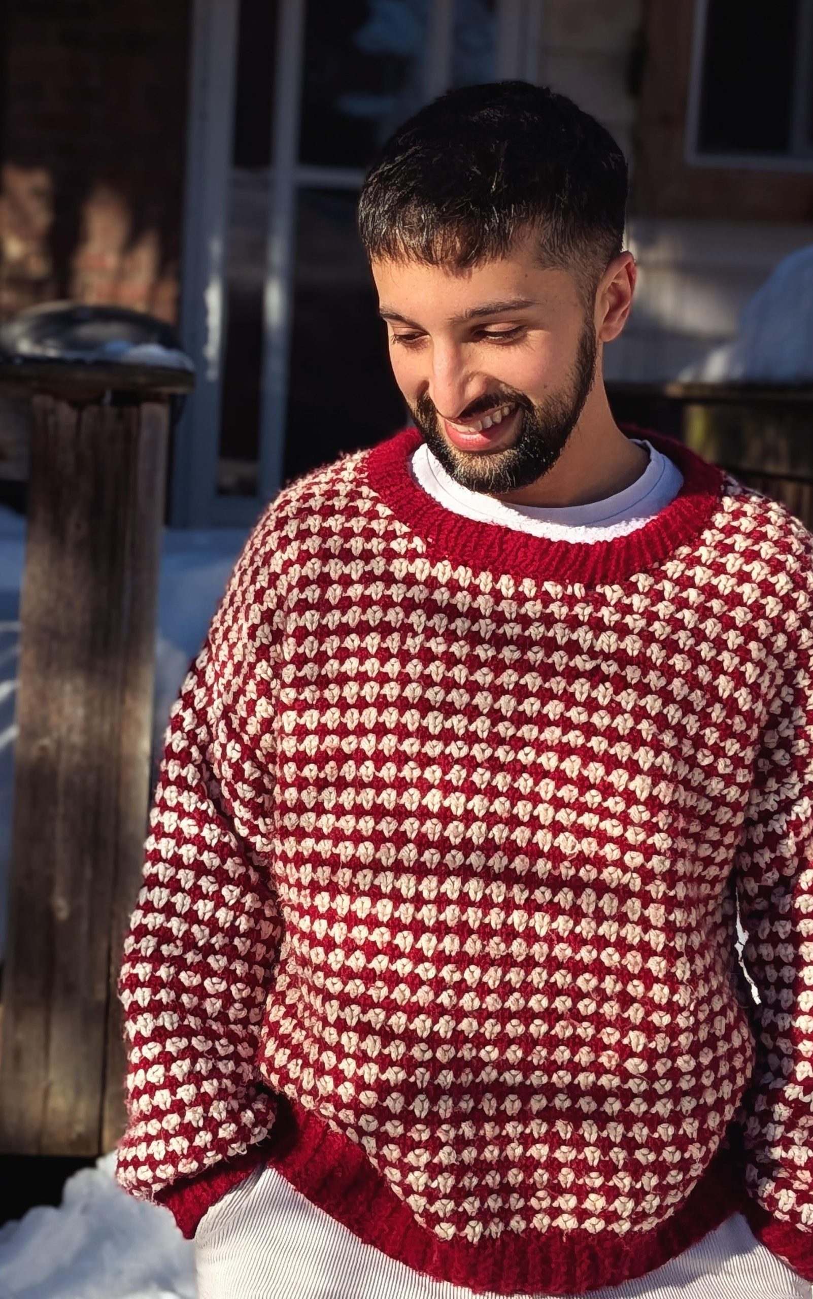 Portrait of Lucas Fothergill smiling outdoors, wearing a red and cream knitted jumper.