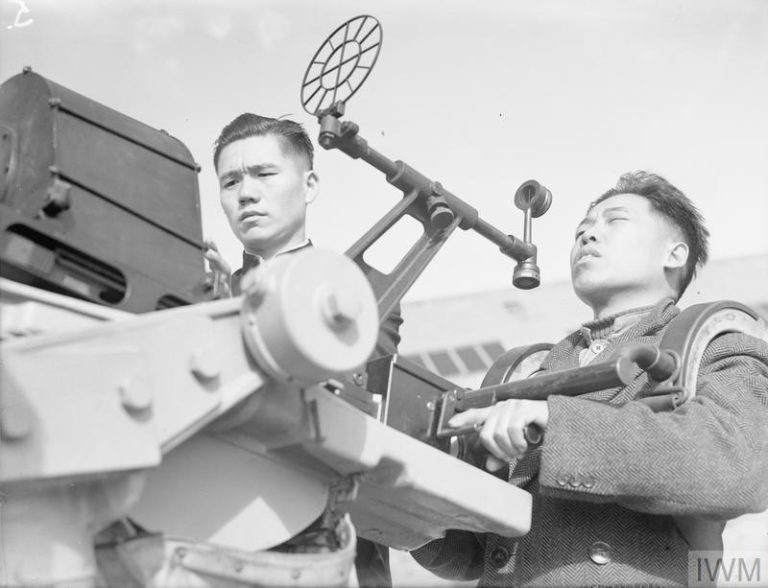 Black-and-white photograph of two young Chinese men operating an anti-aircraft gun during ww2